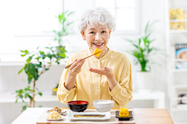 上顎のインプラント治療をして美味しく食事をいただく女性