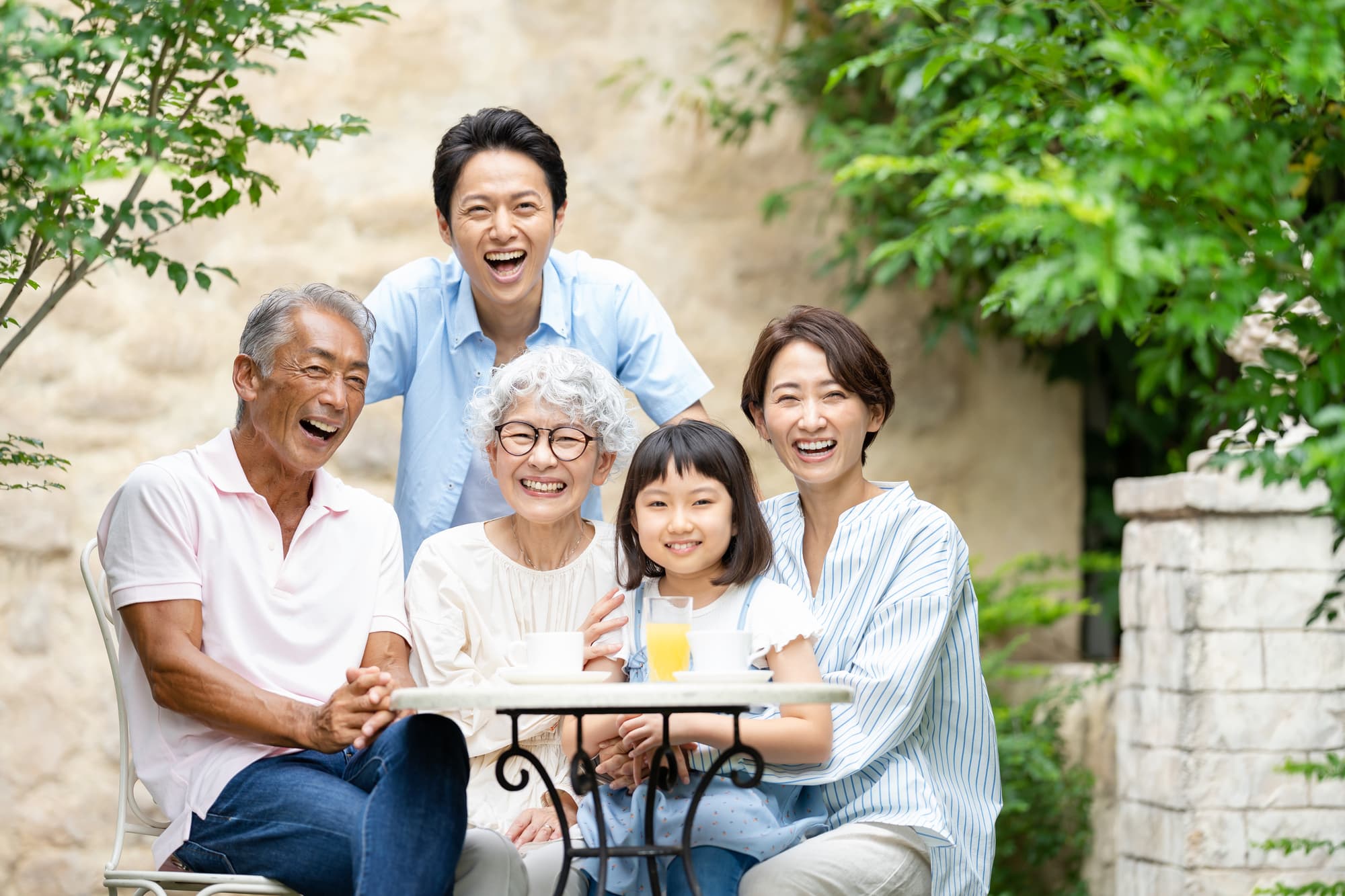 庭で笑顔で過ごす三世代家族