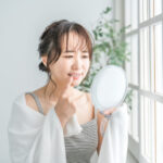 歯ぐきからの出血が気になって鏡を見る女性
