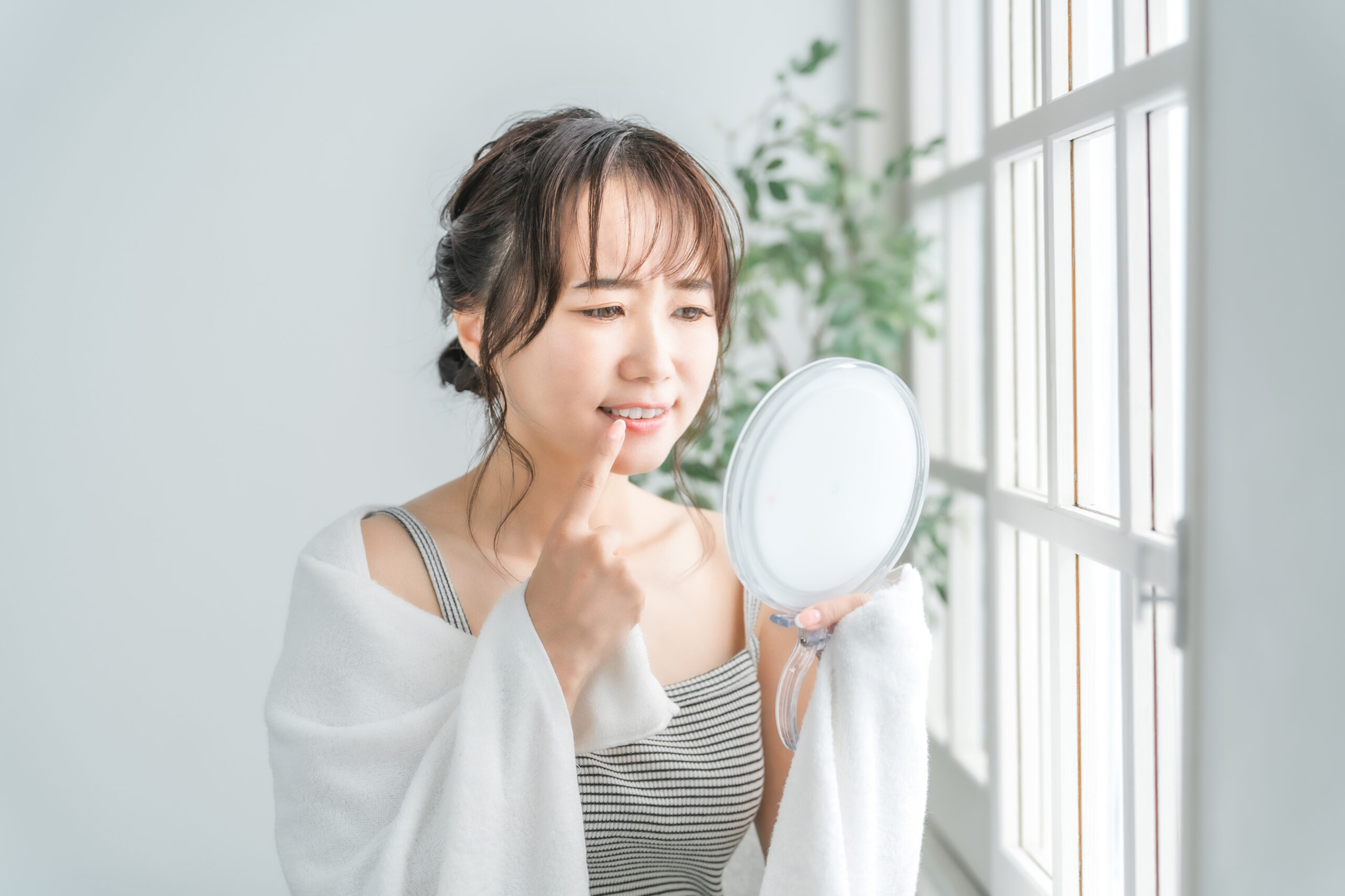 歯ぐきからの出血が気になって鏡を見る女性