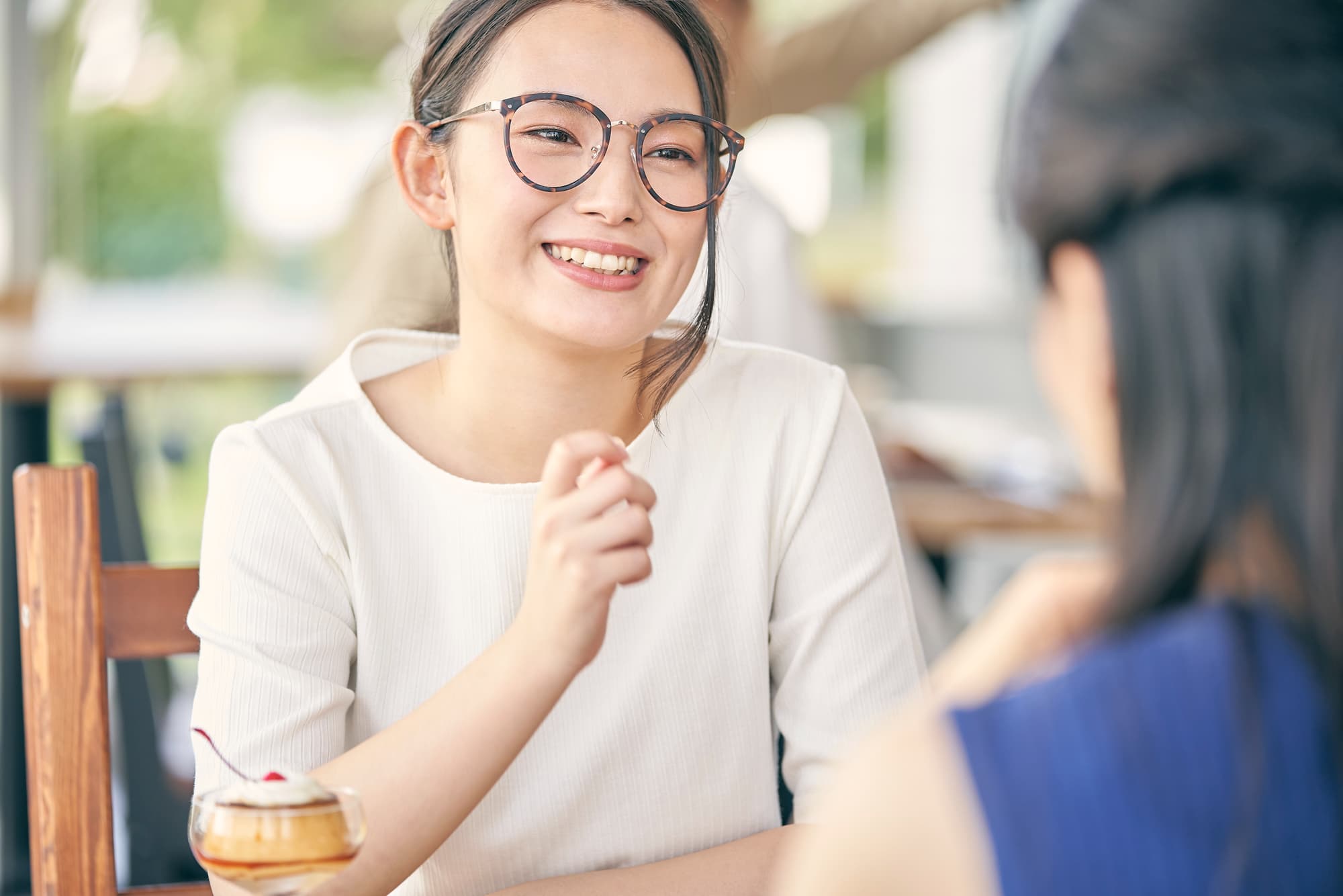 カフェで友人と楽しそうに会話する女性
