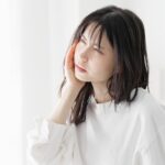 顎関節を押さえて不快そうな顔の女性