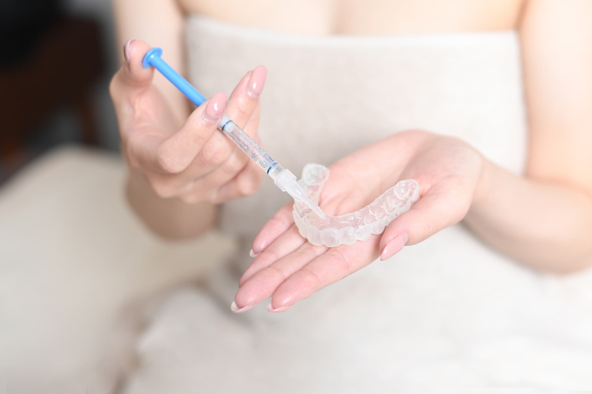 ホームホワイトニングの薬剤をマウスピースに注入する女性の手元